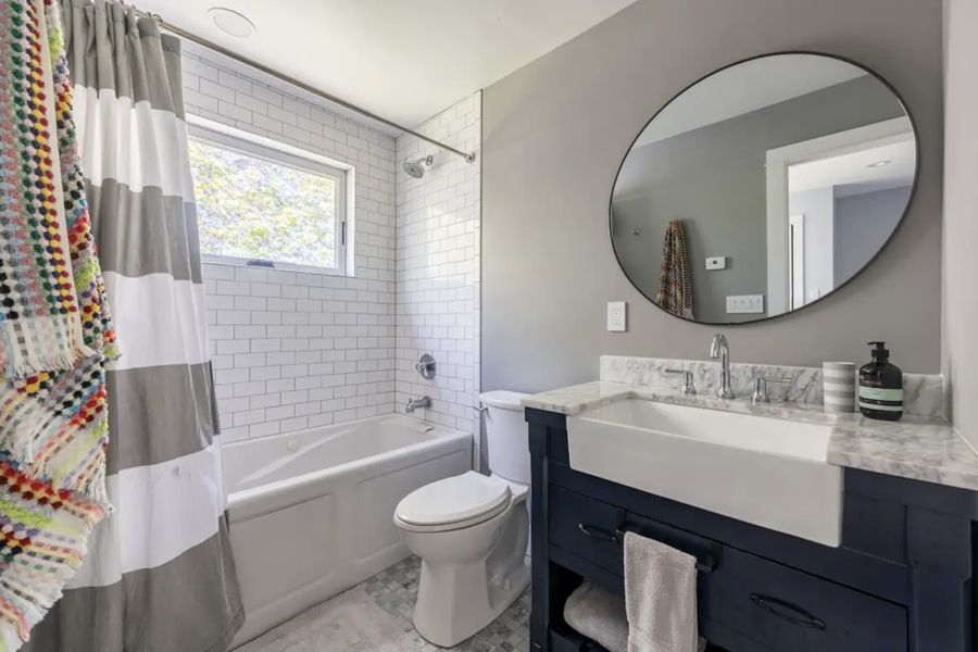 Bathroom with jetted tub and round mirror
